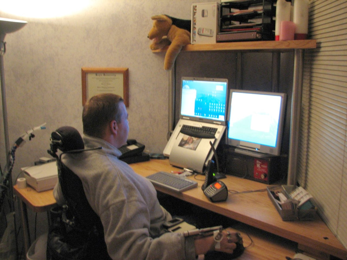Quadriplegic_in_wheelchair_using_Maverick_Corner_Wheelchair_Desk_with_high_monitor_Shelf